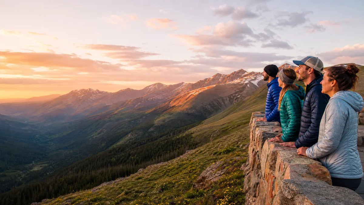 Un petit groupe en polaires et doudounes à un belvédère en pierre au coucher du soleil